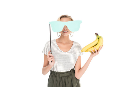 微笑的年轻女子手持香蕉和眼镜的党坚持在白色隔离图片