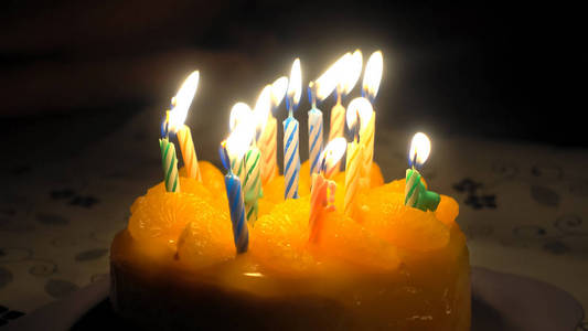 橙色蛋糕庆祝生日五颜六色的蜡烛花边与火