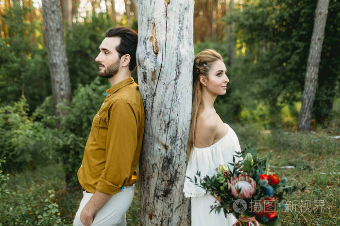 新娘和新郎依靠从不同侧面树。新婚夫妇走在森林中。图稿