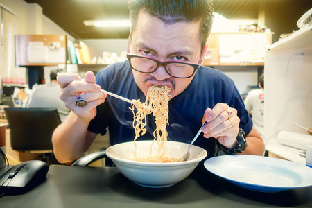 亚洲人吃方便面非常热和辣在办公室地点照片