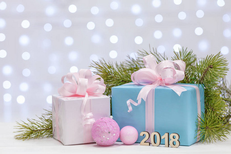 圣诞礼物与大弓包裹在粉红色和裸纸, 躺在一个木质表面云杉树枝。新年2018号