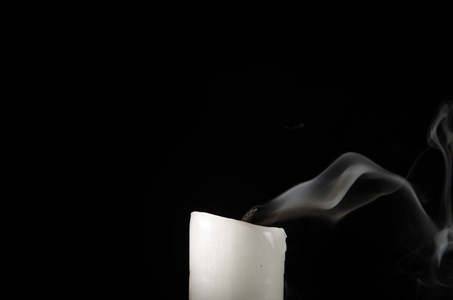 燃烧的蜡烛与褪色的火焰和烟雾在黑色的背景