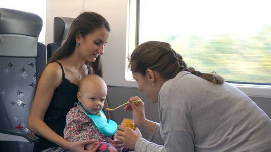两个年轻的女士在火车上喂养婴儿