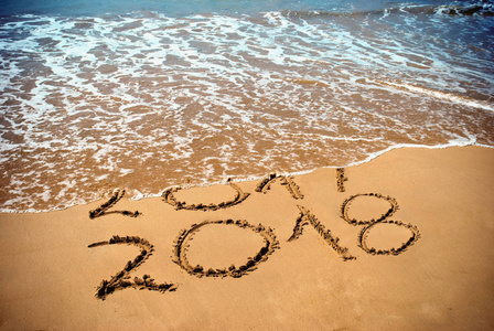 新年2018是未来概念题字2017和2018在海滩沙子, 波浪是覆盖物数字2017。元旦2018新年前夕热带海岛旅游巡礼