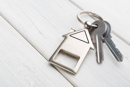 一串钥匙与房子形状的钥匙扣在白色木头