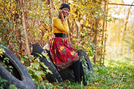 非洲裔美国女孩看黄色和红色的衣服，在金色的秋天 f