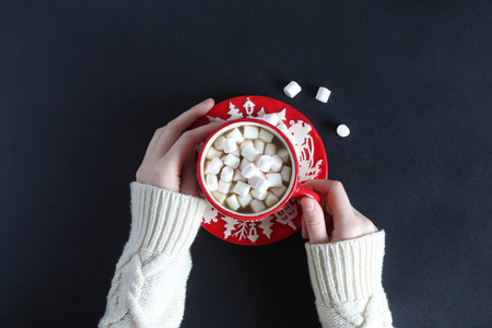 棉花羊毛女手中持有与可可和棉花糖的红色杯子的白色羊毛衫照片