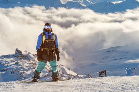 一个专业滑雪与背包站立在雪高在山反对背景低云彩和高加索山在日落期间