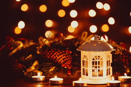 圣诞灯笼与燃烧的蜡烛和花环的老式木桌上的金色散。自由空间