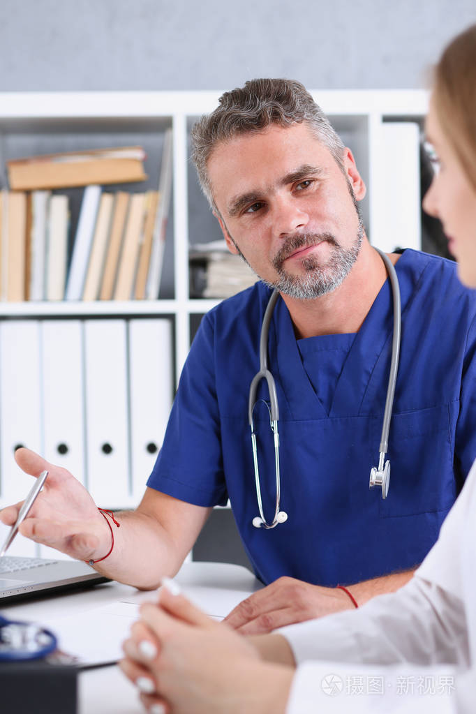 微笑英俊成熟的医生与病人沟通