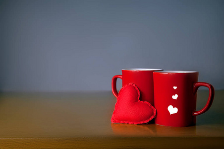 情人节的概念。灰色背景下桌子上的两个红色的玩具红心杯