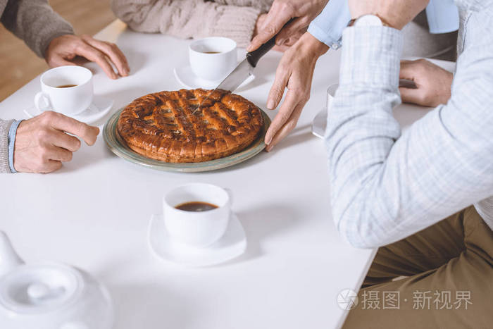 裁剪的女人在桌子上切馅饼的形象, 而朋友坐