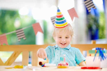 可爱的小男孩开心和庆祝与五颜六色的装饰和蛋糕的生日聚会