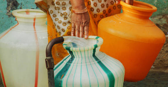 印度水站管灌装塑料水壶。妇女运载水罐