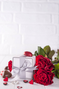 新鲜的红玫瑰和木桌上的礼品盒