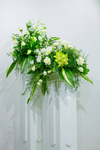 一束白玫瑰, 黄水仙, 绿叶和莲花矗立在大理石架上的花瓶里