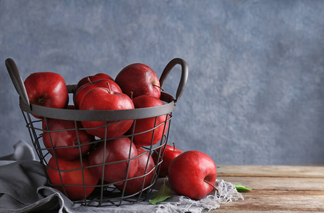 金属篮子与成熟红色苹果在桌