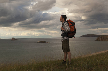 年轻的旅游男子背着背包在湖上, 贝加尔湖, 夏天旅游散步, 自由和幸福