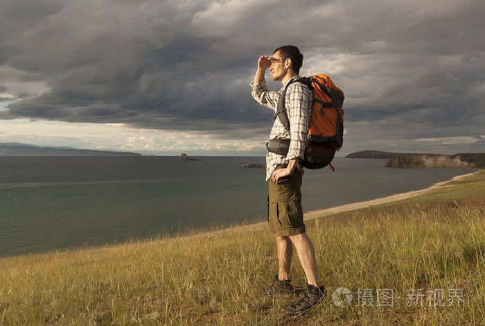 年轻的旅游男子背着背包在湖上, 贝加尔湖, 夏天旅游散步, 自由和幸福