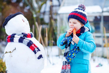 有趣的孩子男孩在冬天的户外堆雪人