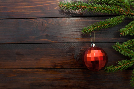 绿色的圣诞树树枝在深色的木制背景下。新的一年背景与一个红色玻璃球。顶部视图