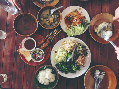 美味的亚洲美食摆在餐桌上。辣猪肉沙司米粉, 烤猪肉配花生酱或糖醋汁配蔬菜。顶部视图。复古色调
