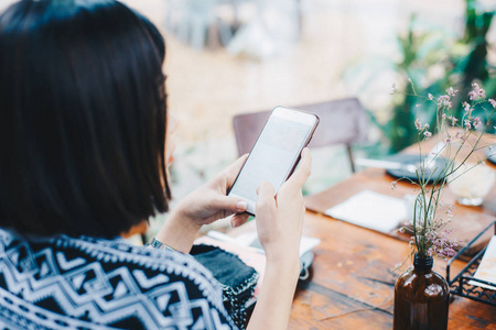 商务亚洲女性使用智能手机, 而坐在老式咖啡店后视图