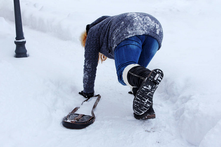 一个女人滑倒在冬天的路上。跌倒在光滑的路