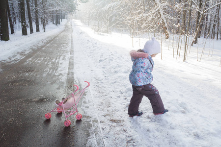 走在冬季保暖服装在雪堆中的小女孩