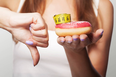 饮食.甜甜圈一个年轻的女孩拿着甜甜圈在她的手, 并显示