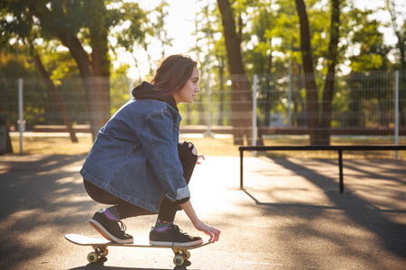 年轻的女孩坐在滑板上。玩滑板。户外活动 生活方式