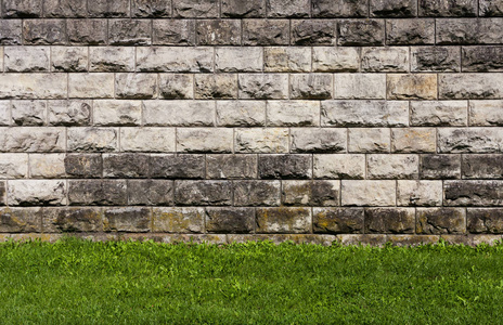 石头和草墙米色和褐色的石头形成一堵墙, 绿色的草照片
