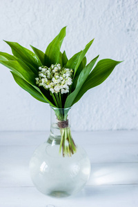在木光背景的小透明花瓶里, 山谷里的百合花。清新的春天心情