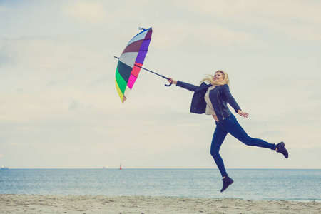 女人在海滩上跳跃着五颜六色的雨伞