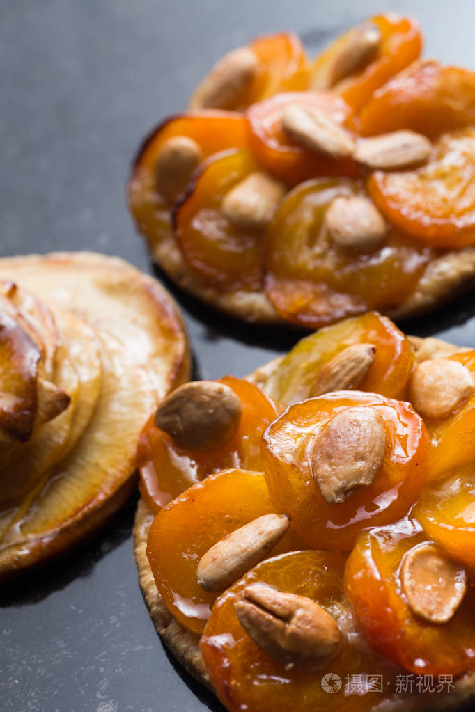 与杏桃和苹果的酸。传统的法国馅饼加黑大理石背景上的水果。装饰的杏仁和薄荷叶子。美味甜点与副本空间特写