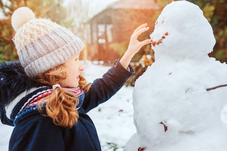 快乐的女孩做雪人在后院的圣诞假期的人。儿童冬季户外活动