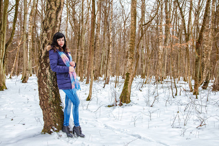 年轻美丽的妇女在森林里漫步在冬天