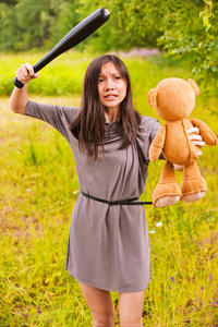 年轻愤怒的女人打玩具熊