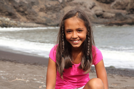 微笑的女孩坐在海滩上