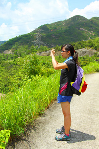 年轻女子背包徒步旅行和拍照