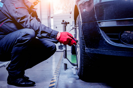 汽车修理工在悬挂调整期间安装传感器.维修服务站车轮对准工作照片