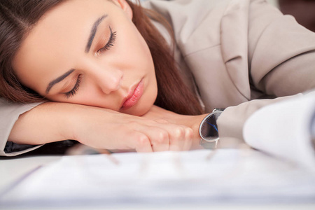 办公室办公桌上的年轻疲惫的女人闭着眼睛睡觉, 型照片