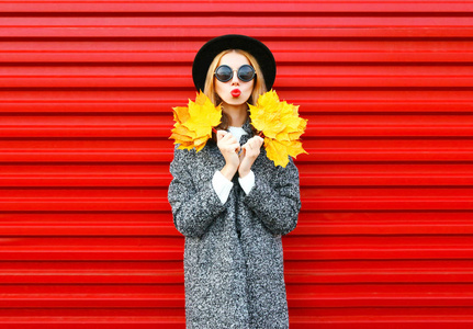时装秋季年轻女子大衣持有黄色枫叶
