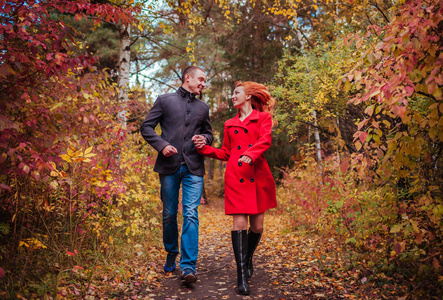 对年轻的夫妇在秋天的树林，多彩的树林中运行