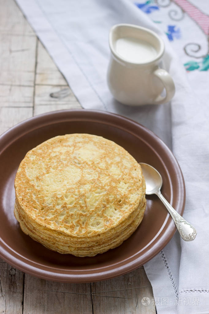 在木桌上的盘子上有酸奶油的俄罗斯薄饼堆 blini