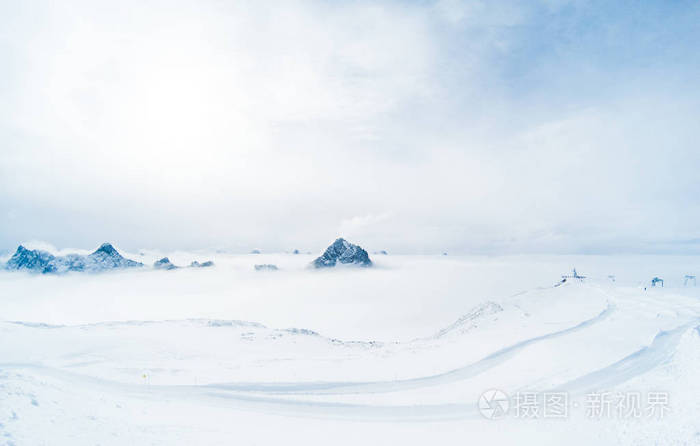 美丽的全景阿尔卑斯山山脉从岩石上方的云层。滑雪跑道沿着悬崖。法国