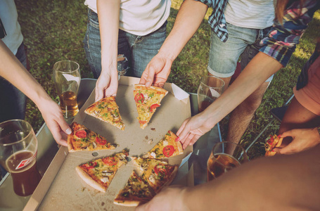 愉快的朋友野餐在公园吃比萨饼