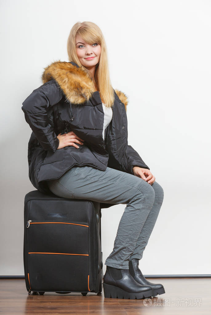 年轻的女人带着手提箱件温暖的外套