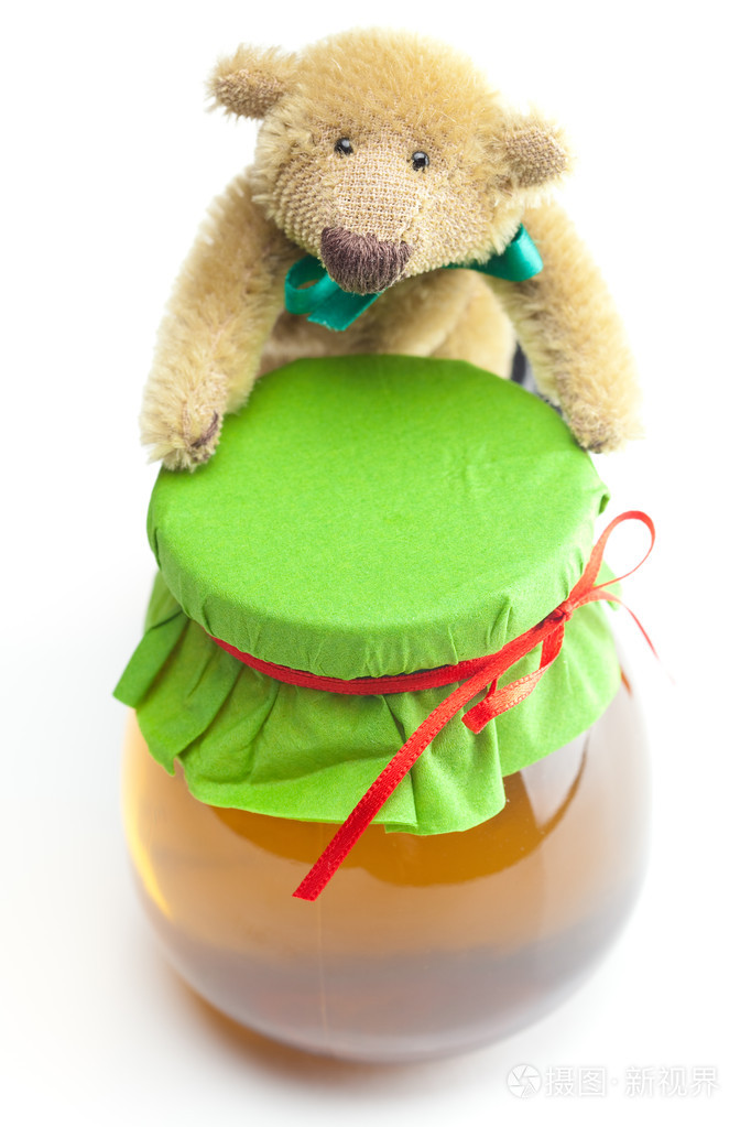 泰迪熊和一罐蜂蜜隔离在白色上