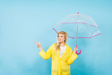 女人穿着雨衣拿着伞指向